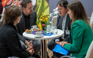 Vier Personen sitzen um einen Café-Tisch und unterhalten sich. Einer davon ist Guido Zeitler, der Vorsitzende der Gewerkschaft NGG