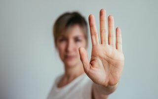 Eine Frau hält ihre Hand zum Stop-Zeichen erhoben in die Kamera. 