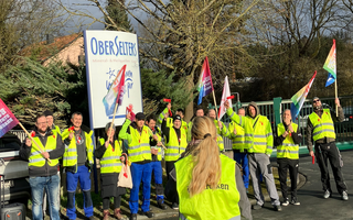 Eine Gruppe von Menschen in neongelben Streikwesten mit Schildern. 