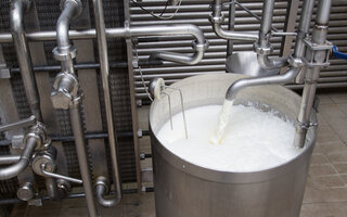 Ein offener Milchtank in einer Milchfabrik, in den gerade Milch fließt. 