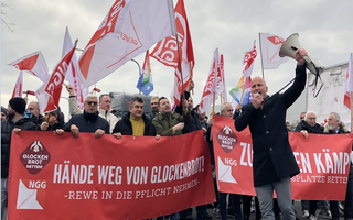 Eine große Gruppe Beschäftigte, die mit großen roten Transparenten gegen die Schließung von Glockenbrot demonstrieren. 