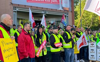 Beschäftigte stehen vor der Brauerei Berliner Kindl-Schultheiss und streiken. 