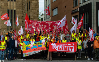 Gruppenbild mit vielen Lieferando-Lieferfahrer und -Lieferfahrerinnen bei einer Demonstration.