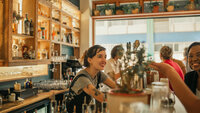Frau steht hinter einem Tresen in einer Bar. 