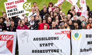 Eine Gruppe Jugendlicher mit Transparenten steht auf einer Wiese.