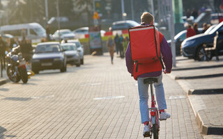 Ein Lieferfahrer fährt auf einem Fahrrad die Straße entlang
